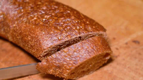 Man cutting bread with a kitchen knife on a wooden board Stock Footage 250099265