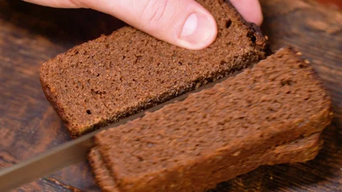 Man cutting bread with a kitchen knife on a wooden board Stock Footage 253719543