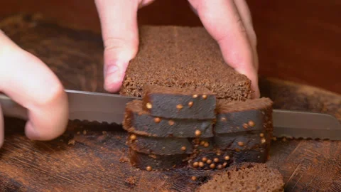 Man cutting bread with a kitchen knife on a wooden board Stock Footage 253719839