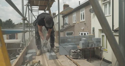 Man cutting into breeze block with circular saw mid-shot Stock Footage 246379837