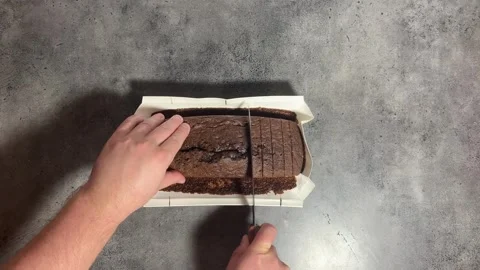 Man cutting brown chocolate cocoa cupcake with knife on gray kitchen table Video stock 295245295