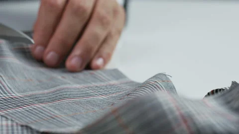 Man Cutting Checked Piece of Material With his Scissors Stock Footage 89343788