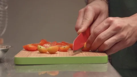 Man cutting cherry tomatoes with a red plastic knife Video stock 75166776