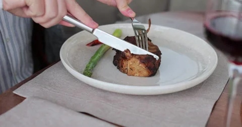 Man cutting cooked rack of lamb. Delicious steak with vegetables on table. Stock Footage 319013200