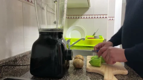 Man cutting cucumber and peeling kiwi fruit Stock Footage 148940189