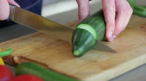 Man cutting a cucumber next to other vegetables Stock Footage 41011786