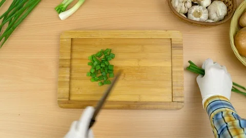 Man cutting fresh chives at the kitchen using hygienic gloves. Stock Footage 108421600