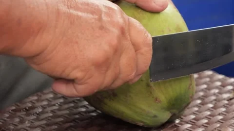 Man Cutting Fresh Green Coconut with a Cleaver Knife Stock Footage 345638464