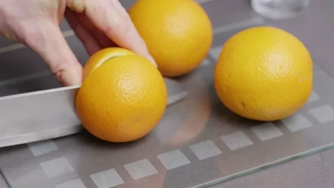 Man cutting fresh oranges into halves to make orange juice Stock Footage 85433743