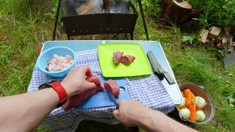 Man cutting fresh raw meat with knife for outdoor picnic barbecue camping l.. Stock Footage 342595087
