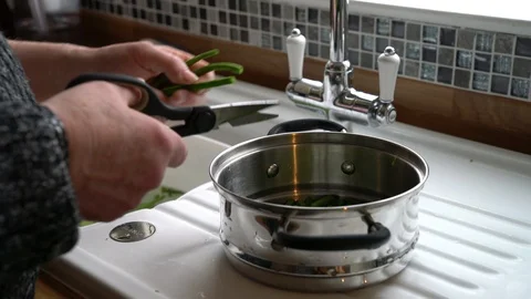 Man cutting green beans using scissors falling into silver pan, 4k Video stock 86979677