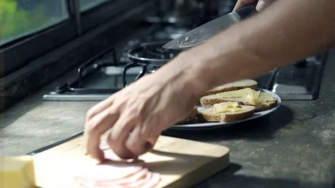 Man cutting ham and preparing sandwich in kitchen, focus on hands Stock Footage 72347489