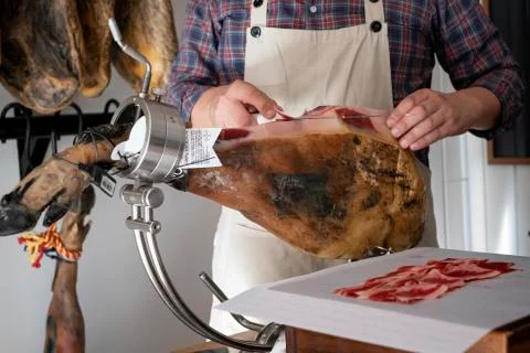 Man cutting ham with a knife in a ham holder Stock Photos