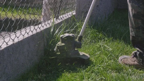 Man Cutting High Grass And Weeds With An Electric Garden Trimmer Видео 126980976