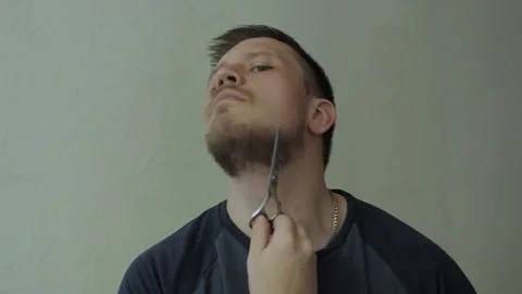 Man cutting his beard with scissors. Video stock 77325100