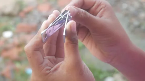 A man is cutting his fingernails using a metal nail clipper Stock Footage 333343267