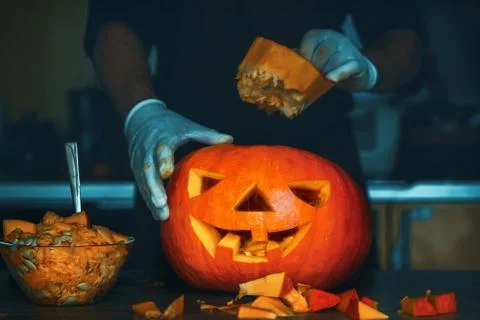 Man cutting a jack-o-lantern pumpkin to halloween celebration. Stock Photos
