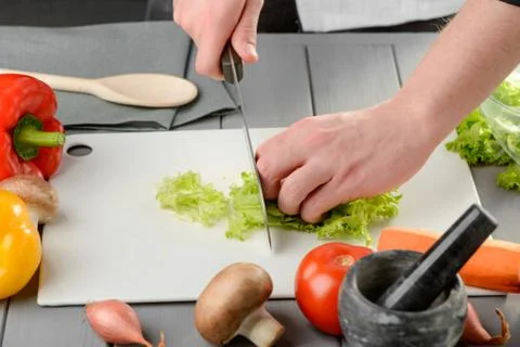 Man cutting a lettuce leaf on a white board Stock Photos