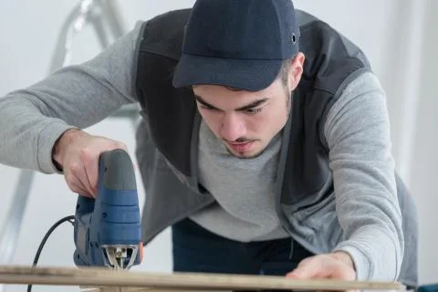 Man cutting material using jigsaw Stock Photos