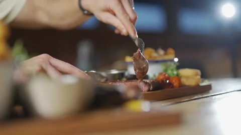 A man is cutting meat with a fork and knife Stock Footage 296056801