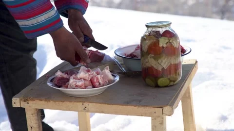 A man cutting meat in snow Stock Footage 245471014