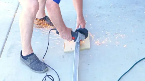 Man Cutting a Metal Bar with an Angle Grinder on a Pathway Stock Footage 336309898