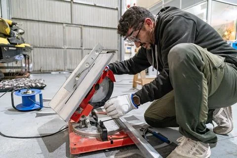 Man cutting metal profile using miter saw in workshop Stock Photos
