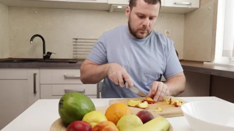 Man cutting nectarine in the kitchen, middle-aged person home cooking, fres.. Stock Footage 305388408