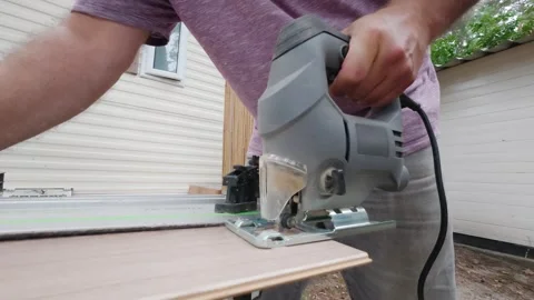 Man cutting oak laminate planks while wooden splinters fly through the air Stock Footage 340566057