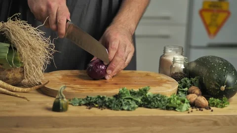 A man is cutting an onion on a table full of fresh vegetables. Guy cooking dinne Stock-Footage 141776812