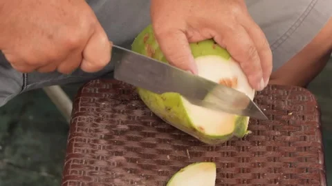 Man Cutting Open Fresh Green Coconut with Large Knife Stock Footage 345637547