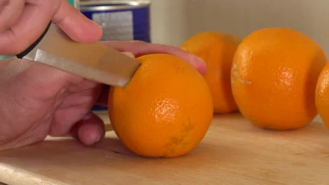 Man cutting orange in half with knife Stock Footage 146655470