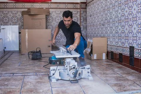 Man cutting a panel with an electric machine to install a kitchen cabinet Stock Photos