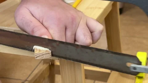 Man cutting piece wood using a manual saw Joinery craftsmanship in progress shot Stock Footage 309533716