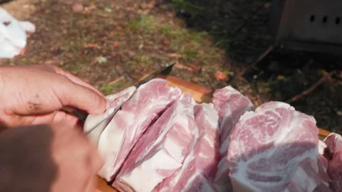 Man cutting raw lamb meat on wooden board outdoors in slomo Stock Footage 319661608