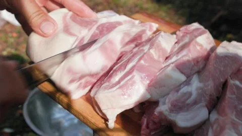 Man cutting raw lamb meat on wooden board outdoors in slomo Stock Footage 319661715