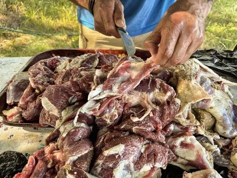 Man cutting raw lamb meat on street, traditional cutting process, cooking fresh Stock Photos
