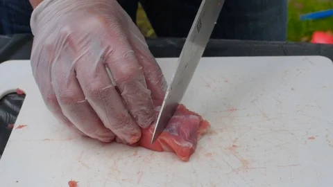 Man cutting the raw meat on a white board in a garden Stock Footage 75844829