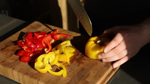 Man cutting red and yellow peppers on board Stock Footage 301990977