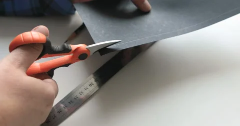 A man cutting a sheet of paper with a pair of scissors Stock Footage 107720186