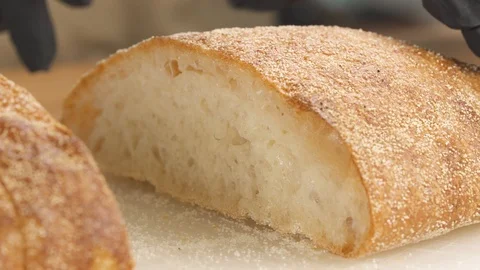 A man cutting a slice of freshly baked crispy ciabatta bread. Isolated, on Stock Footage 107466822