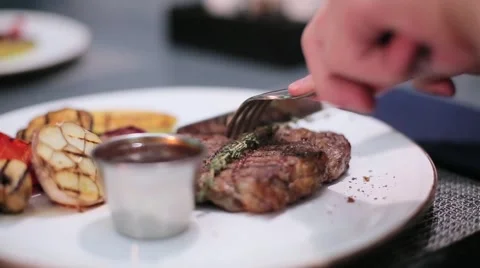 Man cutting a steak on the plate Stock Footage 67863001