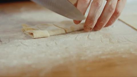 Man cutting thin strips of dough on a table with flour Stock Footage 274607703