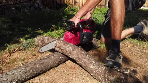 Man cutting through a wooden log with cordless chainsaw Stock Footage 345563593