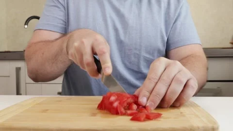 Man cutting tomatoes in the kitchen, middle-aged Caucasian preparing lunch .. Stock Footage 306530623