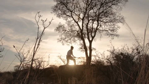 Man cutting tree with axe at the top of the mountain at sunset Vidéo 122761262