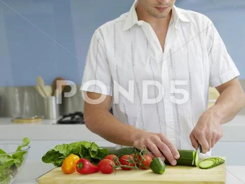 Man Cutting Vegetables In Domestic Kitchen Stock Photos