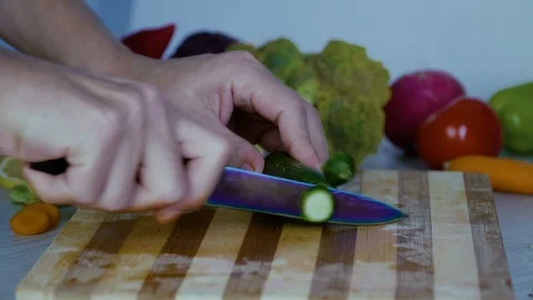 Man is cutting vegetables in the kitchen, slicing cucumber, close up view Stock Footage 98202609