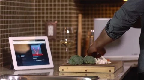 Man cutting vegetables in kitchen while using tablet computer Stock Footage 47780951