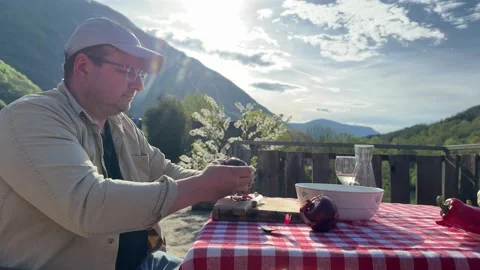 Man Cutting Vegetables on Outdoor Table in Scenic Countryside Stock Footage 333523417